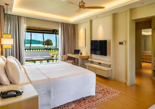 a hotel room with a large white bed and a television at Pelangi Beach Resort & Spa, Langkawi in Pantai Cenang
