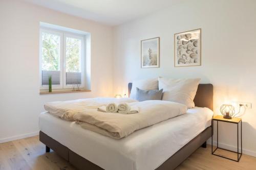 una camera da letto con un grande letto bianco con due asciugamani di Villa Dornkamp 2 - Luxuriöse Ferienwohnung für 4 Personen inklusive Garten und Sauna a Timmendorfer Strand