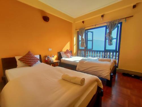 una camera d'albergo con due letti e una finestra di Bandipur Kaushi Inn a Bandipur