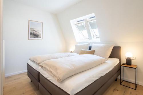 a bedroom with a large white bed with a window at Villa Dornkamp 6 - Luxuriöse Ferienwohnung für 2 Personen inklusive Balkon und Sauna in Timmendorfer Strand