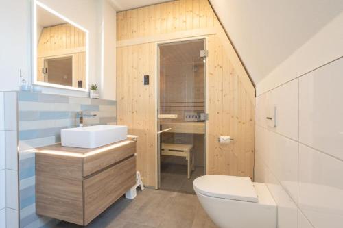 y baño con aseo blanco y lavamanos. en Villa Dornkamp 6 - Luxuriöse Ferienwohnung für 2 Personen inklusive Balkon und Sauna en Timmendorfer Strand