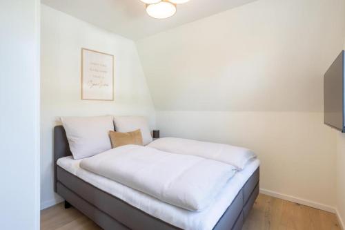 Bett mit weißer Bettwäsche in einem weißen Zimmer in der Unterkunft Villa Dornkamp 4 - Luxuriöse Ferienwohnung für 4 Personen inklusive Balkon und Sauna in Timmendorfer Strand