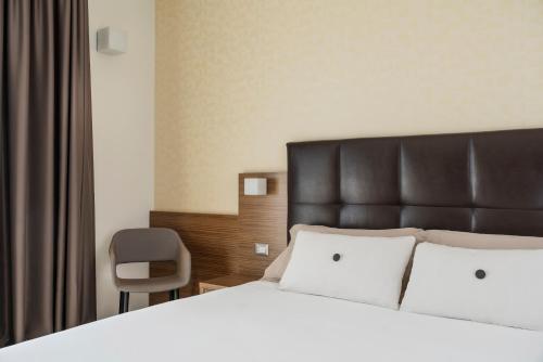 a bedroom with a bed with a black headboard and a chair at Aqua Hotel in Rimini