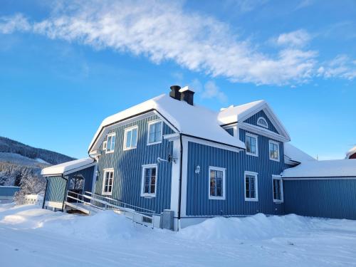 una casa azul con nieve encima en Wärdshuset Klarälvdalen en Sysslebäck