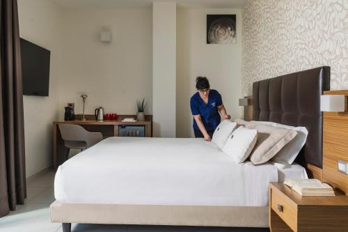 a man is standing next to a large bed at Aqua Hotel in Rimini