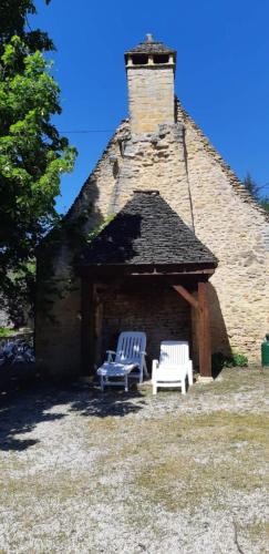 2 chaises blanches assises devant un bâtiment dans l'établissement Le fournil de la Blogeonie, à Saint-Geniès