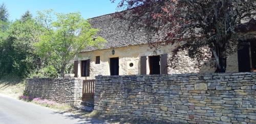 un antiguo edificio de piedra junto a una pared de piedra en Le fournil de la Blogeonie, en Saint-Geniès