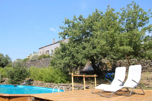 una terraza con 2 sillas y una mesa junto a la piscina en Casa Etnea, en Trecastagni