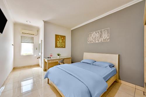 a bedroom with a blue bed and a desk at Cinere Inn & Residence in Cinere