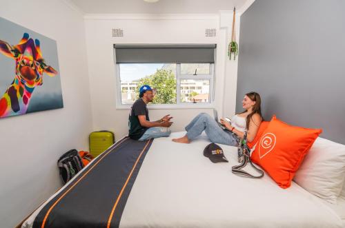 Un uomo e una donna seduti su un grande letto di Never at Home Kloof Street a Città del Capo