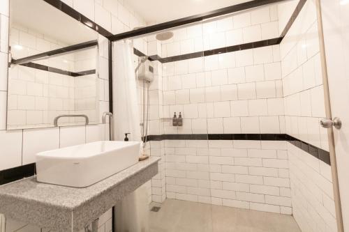 a white bathroom with a sink and a shower at Ananzitra Hotel in Kanchanaburi