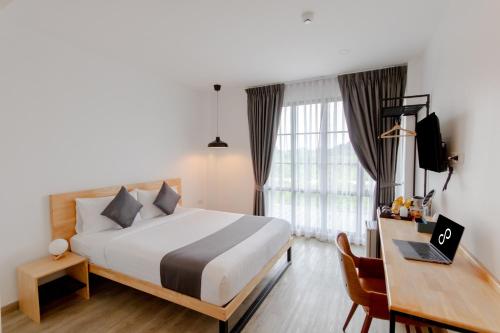 北碧Ananzitra Hotel的一间卧室，配有一张床和一张带笔记本电脑的书桌
