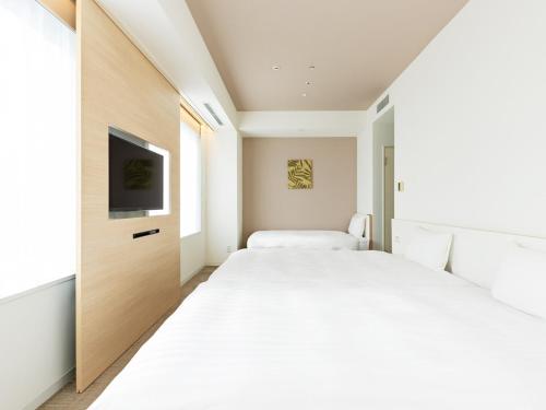 a bedroom with two beds and a tv at The OneFive Sendai in Sendai
