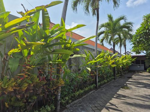 a fence with plants and palm trees in front of a house at The Bagus in Kerobokan
