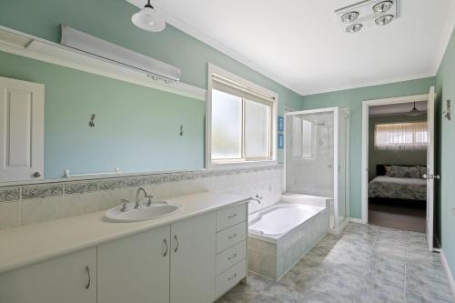 ein Badezimmer mit einer Badewanne, einem Waschbecken und einer Badewanne in der Unterkunft Oceanview Family Retreat in San Remo