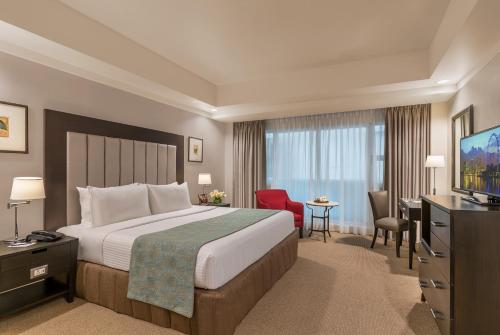 a hotel room with a bed and a flat screen tv at Somerset Millennium Makati in Manila