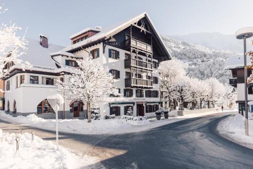 a building on a street with snow covered trees at Posthotel Taube in Schruns-Tschagguns