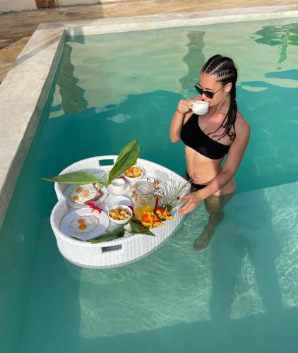 a woman in the water with a tray of food in a pool at Chunga Changa in Matemwe