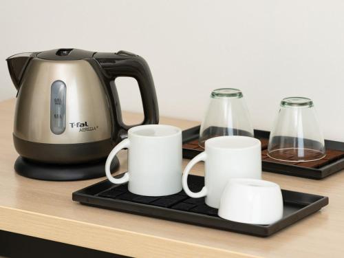 a tea kettle and three white cups on a counter at The OneFive Sendai in Sendai