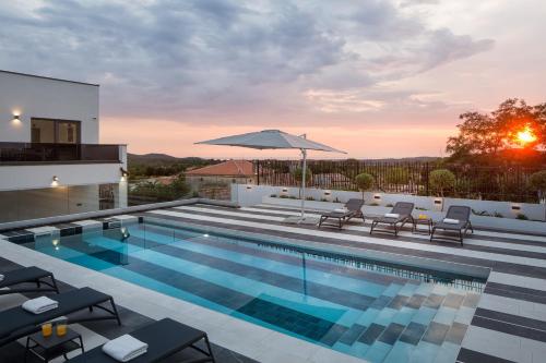 una piscina con sillas y una sombrilla en la parte superior de una casa en Modern villa Dea with jacuzzi and pool in Porec, en Flengi