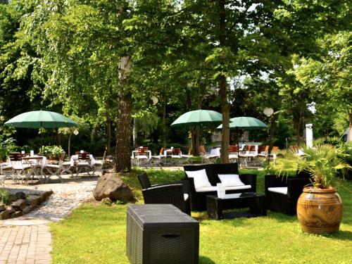 un giardino con sedie, tavoli e ombrelloni di Dein Gutshof Hotel & Ferienwohnungen a Görlitz