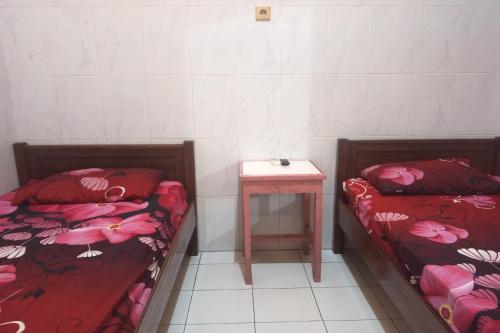 two beds in a room with a side table at Wisma Pelita Syariah Tegal in Tegal
