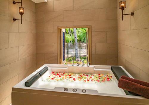 a bathroom with a tub filled with red flowers at Pelangi Beach Resort & Spa, Langkawi in Pantai Cenang