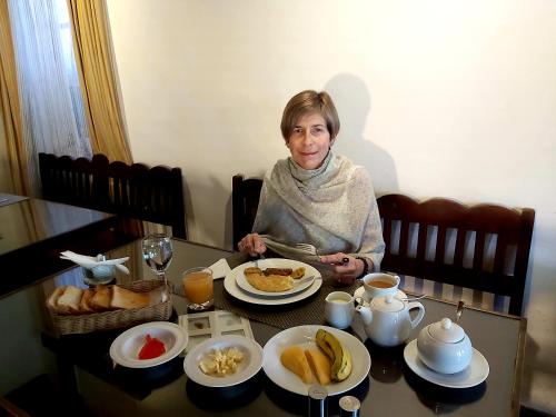 a woman sitting at a table with breakfast food at The Golf Green City Bungalow in Nuwara Eliya