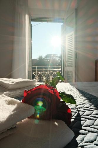 a flower on a bed with towels and a window at Locanda Milano 1873 in Brunate