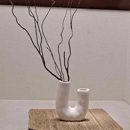 a white vase with some branches in it at Soban Stay in Busan
