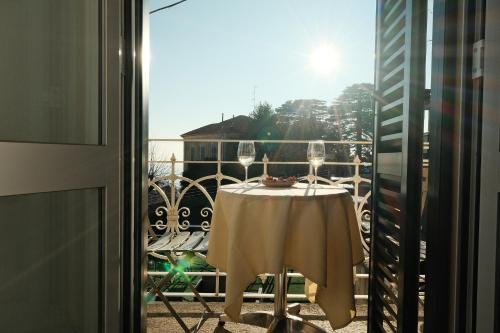 a table with two wine glasses on a balcony at Locanda Milano 1873 in Brunate