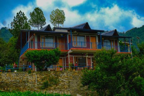 a large house on top of a stone wall at Saanidhya Homestay in Mukteswar