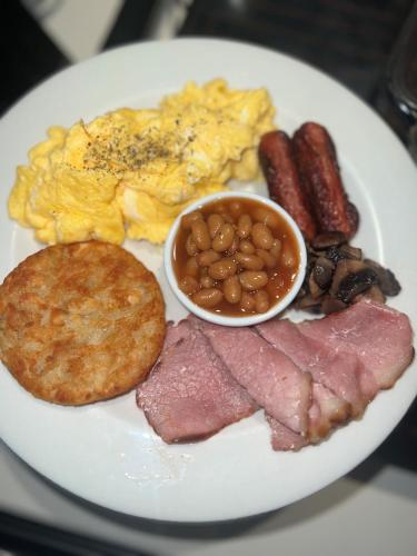 a plate of breakfast food with ham eggs sausage and beans at Sir Roys Guest House in Port Elizabeth