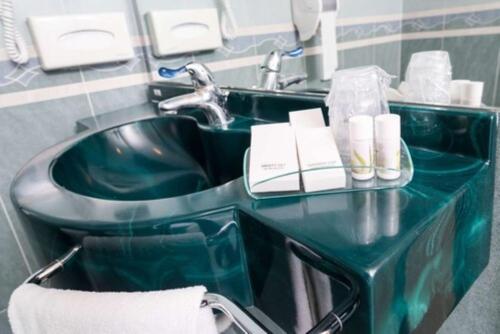 a green bathroom sink with a book on it at Blu Hotel - Sure Hotel Collection by Best Western in Collegno