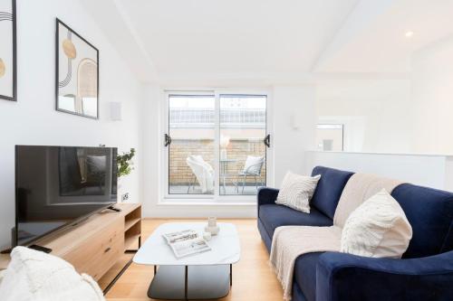 ein Wohnzimmer mit einem blauen Sofa und einem TV in der Unterkunft Fitzrovia & Soho with Balcony - CityApartmentStay in London
