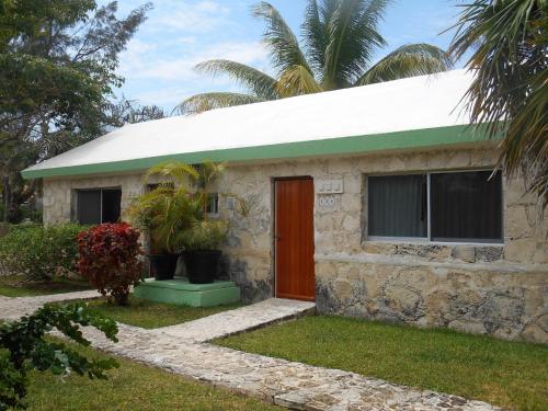 a stone house with a green roof and a red door at Hotel Club Akumal Caribe in Akumal