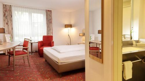 ウンターシュライスハイムにあるHotel Alarunのベッド、テーブル、椅子が備わるホテルルームです。