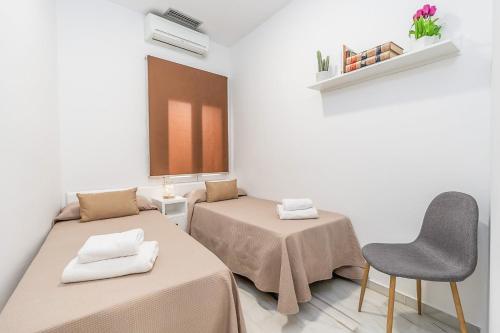 una camera con due letti e una sedia di GRX Gran vía Catedral a Granada