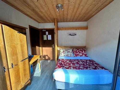 a small bed in a room with a wooden ceiling at Hotel Le Soly in Morzine