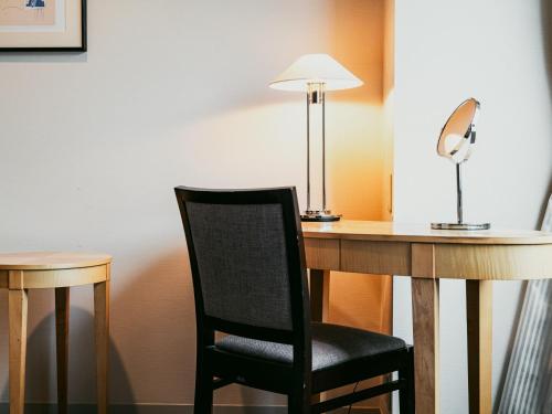 a chair sitting in front of a desk with a lamp at Oarks Canal Park Hotel Toyama in Toyama