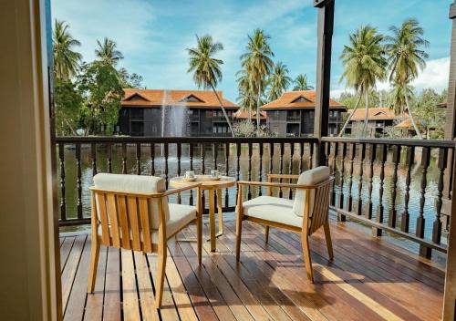a table and chairs on a deck with a view of the water at Pelangi Beach Resort & Spa, Langkawi in Pantai Cenang