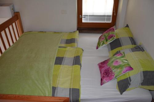 a bed with green and yellow sheets and pillows at Apartmaji Kobal in Zoll