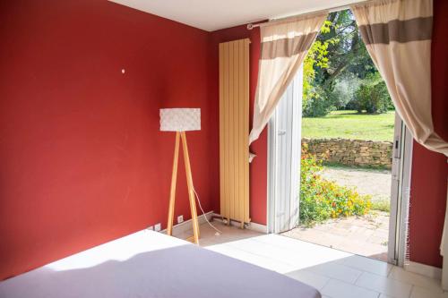 a bedroom with a red wall with a lamp and a doorway at La Magnanerie, 16 personnes avec piscine privée in Bagnols-sur-Cèze