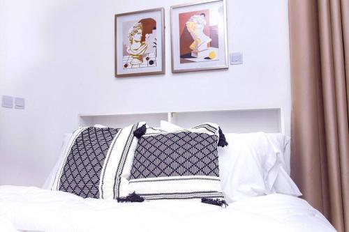 a white bed with two pictures on the wall at Harmony Villa in Tema