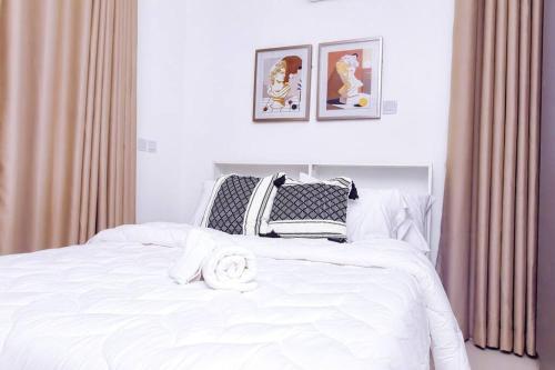 a bedroom with a white bed with two pictures on the wall at Harmony Villa in Tema