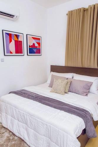 a bedroom with a large white bed with three pictures on the wall at Harmony Villa in Tema