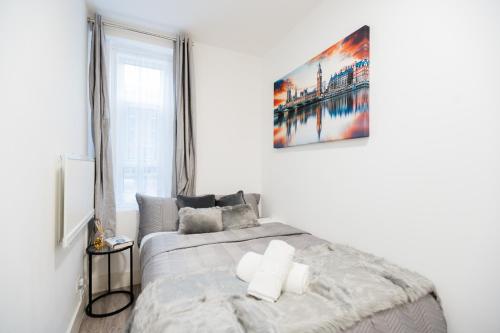 a bedroom with a bed and a painting on the wall at Cozy 1 Bedroom apartment, 30 mins to Oxford street by tube C in London