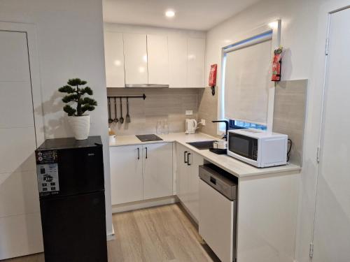 a small kitchen with a black refrigerator and a microwave at Cosy Secure comfortable for two in Canberra in Hall