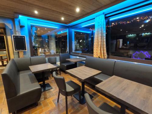 a restaurant with wooden tables and chairs and blue lights at Hotel Le Soly in Morzine