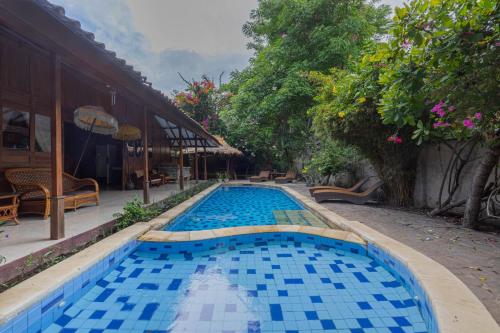 a swimming pool with blue tiles in a yard at Omah Gili Hotel in Gili Air